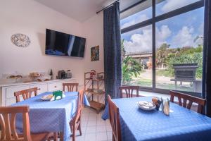 una cucina e una sala da pranzo con due tavoli e una TV di IL VIVAIO Bed and Breakfast a Santa Teresa di Riva