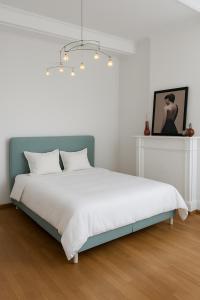 een slaapkamer met een wit bed met een blauw hoofdeinde bij La Belle Époque Apartment in Luxemburg