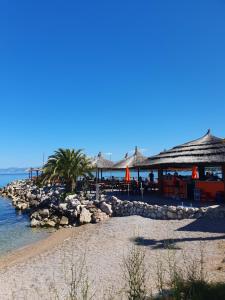 a beach with tables and umbrellas and the ocean at Apartment Lavanda Ruzmarin in Njivice