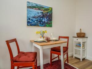 mesa de comedor con 2 sillas y una pintura en 1 Bed in Charmouth 57185, en Charmouth
