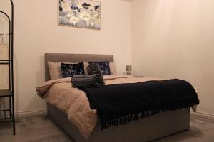 a bedroom with a bed with black blankets and pillows at Luxe Entire 3 Bed Home - LHR 15 mins - London City 35 mins in Denham +18 photos
