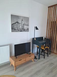 ein Wohnzimmer mit einem Schreibtisch, einem TV und einem Tisch in der Unterkunft Nordic View Residence in Şelimbăr