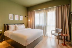 une chambre d'hôtel avec un grand lit et une chaise dans l'établissement grey l studio apartments Downtown Cairo Ouzonian House, au Caire