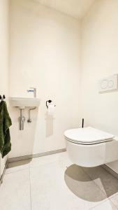 a white bathroom with a toilet and a sink at Appartement Porte Bonheur in Rochefort