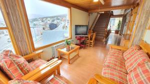a living room with couches and a large window at Hosteria Chalp in Ushuaia