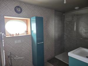a bathroom with a shower and a sink and a clock at AU TEMPS JADIS - Gîte Atypique dans une ancienne Etable Cour privée in Gosnay