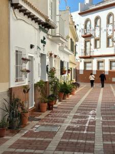 two people walking down a street in a city at Carihuela Home in Torremolinos