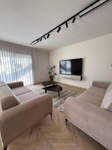 a living room with two couches and a flat screen tv at RASHI6 Boutique Villa in Netanya