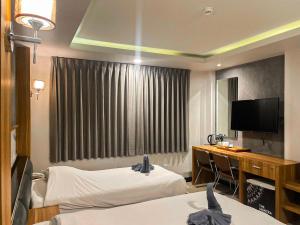a hotel room with two beds and a desk and a television at The Mantra Hotel Kata Noi in Kata Beach