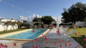 a swimming pool with white lounge chairs next to a house at Masseria Mammella in Monopoli