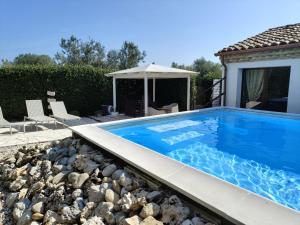 a swimming pool in a backyard with rocks and an umbrella at Il Giardino Di Epicuro in Rocca San Giovanni