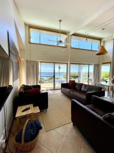 a living room with couches and a view of the ocean at Moonrise Cove in Pelican Lagoon