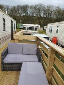 a porch with a couch on a wooden deck at Static Caravan situated at Wigbay, Stranraer in Stranraer +28 photos