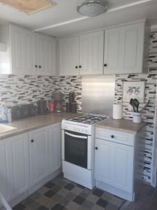 a kitchen with white cabinets and a stove top oven at Static Caravan situated at Wigbay, Stranraer in Stranraer