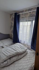 a bed with a blue curtain and a window at Static Caravan situated at Wigbay, Stranraer in Stranraer +29 photos