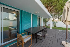 eine Holzterrasse mit einem Tisch und Stühlen auf einem Haus in der Unterkunft Villa Prainha in Alvor