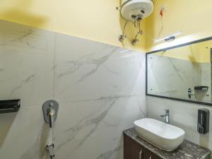 a white bathroom with a sink and a mirror at The Hosteller Rishikesh, Ganges in Rishīkesh
