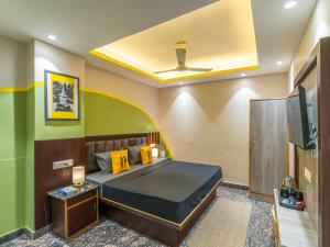 a bedroom with a bed with yellow pillows and a tv at The Hosteller Rishikesh, Ganges in Rishīkesh