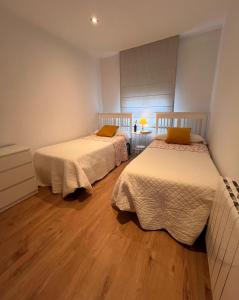 two beds in a room with wooden floors at Casa Rural Las Candelas in San Vicente de Alcántara +18 photos