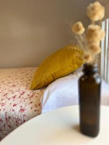 a bottle of oil on a bed with a yellow pillow at Casa Rural Las Candelas in San Vicente de Alcántara