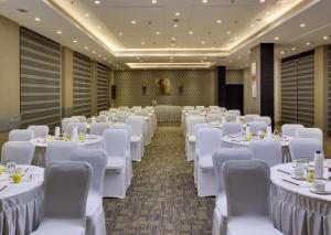 a banquet hall with white tables and chairs at Hotel Suba Grand Dahej in Dahej