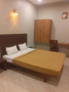 Un dormitorio con una cama grande con una manta amarilla. en Hotel Sudarsh Deluxe, en Satara