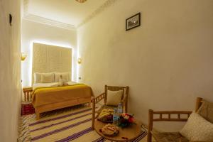 a bedroom with a bed and a table and chairs at Riad des remparts Marrakech in Marrakech