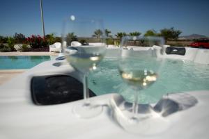 two glasses of white wine sitting on a table next to a swimming pool at Nadine sea side villas in Larnaca