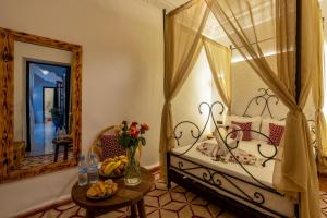a bedroom with a bed with a table and a mirror at Riad des remparts Marrakech in Marrakech