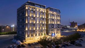 a lit up building with cars parked in a parking lot at Sumou Al Khobar Corniche in Al Khobar