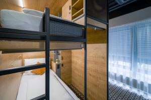 twee stapelbedden in een kamer met een raam bij CHORS like a hotel - Capsule & NFT Boutique Hostel Bratislava - City Center in Bratislava