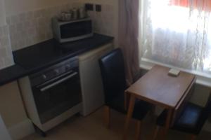 a small kitchen with a table and a microwave at Glen Villa 1 Sleeps 4 Near Beach in Great Yarmouth