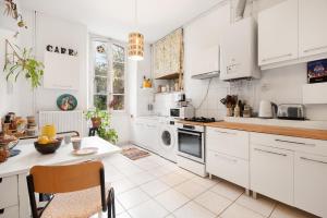 une cuisine avec des appareils blancs et une table avec des chaises dans l'établissement T3 Havre de paix 6p - 115m Cœur Saint Sernin Toulouse - PKG 3 min, à Toulouse