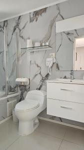 a white bathroom with a toilet and a sink at Hotel Ágora in Viña del Mar