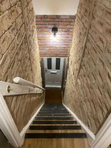 a staircase with a brick wall and a door at Stylish & Spacious 2 Storey, 3 Bed Apartment in Kent