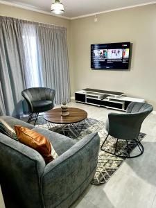 un salon avec un canapé, des chaises et une télévision dans l'établissement Cozy Loft, à Gaborone