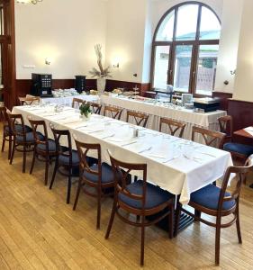 a long table with white tables and chairs in a room at Mádi Kúria Hotel és Rendezvényközpont in Mád