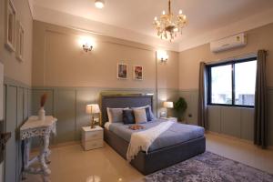 a bedroom with a bed and a chandelier at EKO STAY Gold - Gatsby Villa in Lonavala