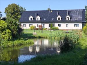 a house with solar panels on its roof next to a pond at Apartamenty TUTERRA I in Zabagnie