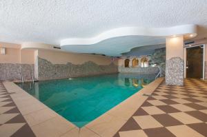 a swimming pool in a hotel with a checkered floor at Centro Appartamenti Vacanze in Mezzana