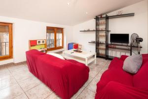 a living room with two red couches and a tv at Poble tranquil prop de Tarragona i Portaventura in Catllar