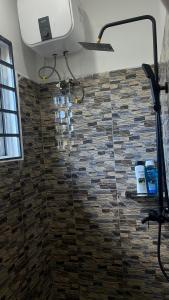 a bathroom with a shower with a stone wall at Amoy River Lodge in Moshi +24 photos