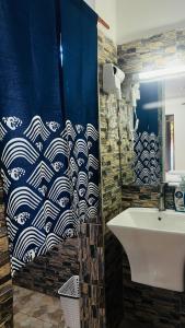 a bathroom with a blue and white shower curtain and a sink at Amoy River Lodge in Moshi