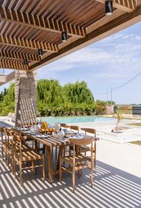 a wooden table and chairs on a patio with a pool at Allure Retreat Villa in Lefkada Town