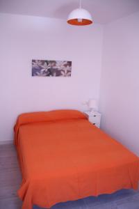 a bed with an orange bedspread in a white room at Apartamento Orange Triana centro in Seville