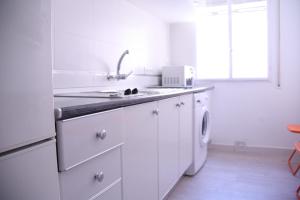 cocina blanca con fregadero y lavavajillas en Apartamento Orange Triana centro, en Sevilla