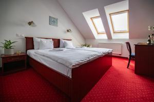a bedroom with a large bed with red carpet at Mádi Kúria Hotel és Rendezvényközpont in Mád
