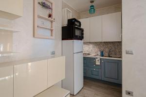 a small kitchen with a white refrigerator and blue cabinets at Giardino, Piscina e Posto Auto - Relax con Vista Mare in Bergeggi