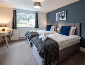 two beds in a bedroom with blue walls and a desk at Kinsale House by Cliftonvalley Apartments in Brislington +48 photos