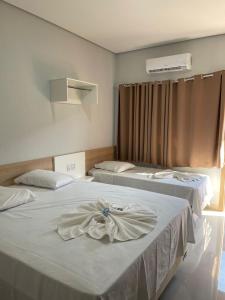 - 2 lits dans une chambre d'hôtel avec une robe dans l'établissement Vitalliti Hotel, à Alta Floresta